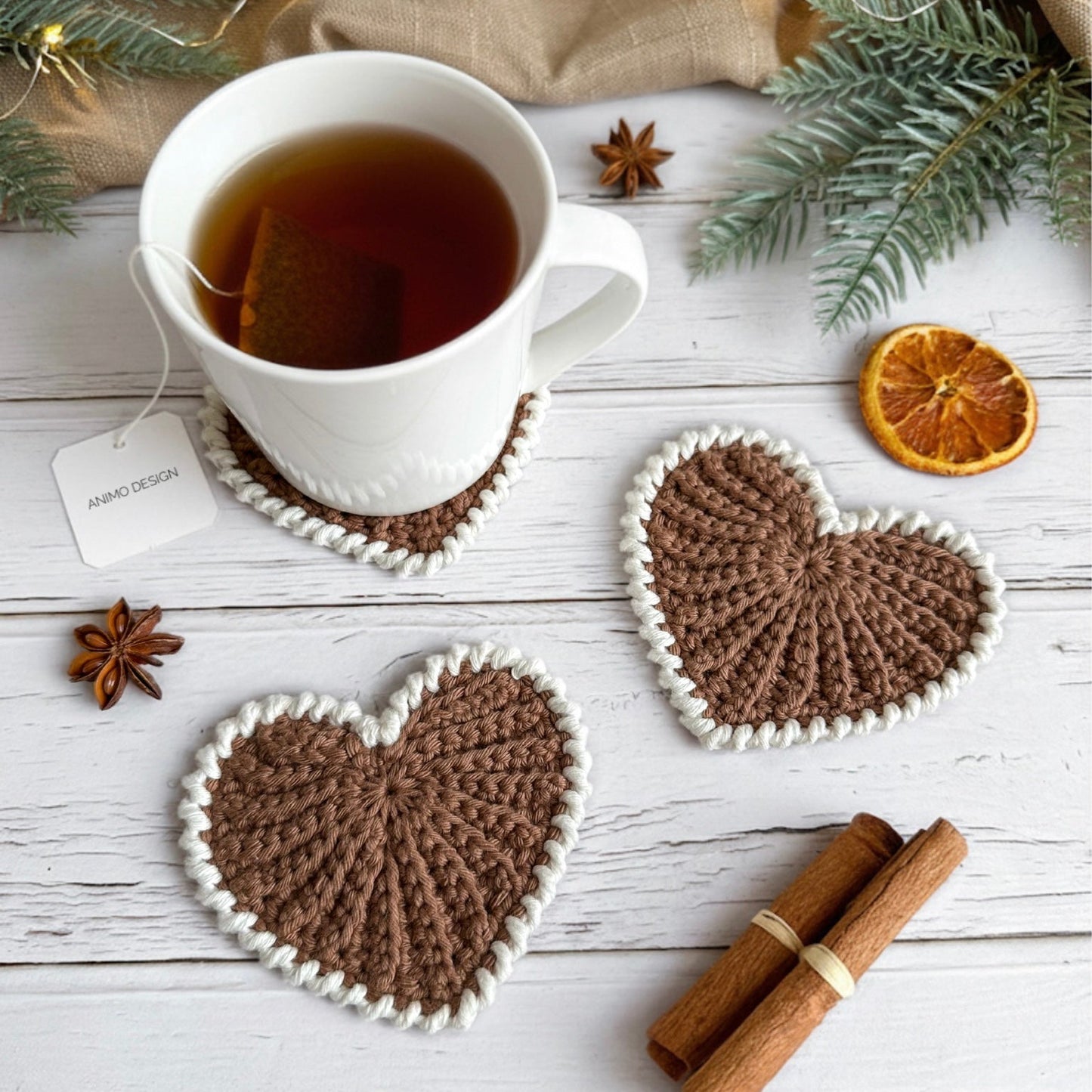 Heart-shaped crochet coasters with a cup of tea on a wooden surface.
