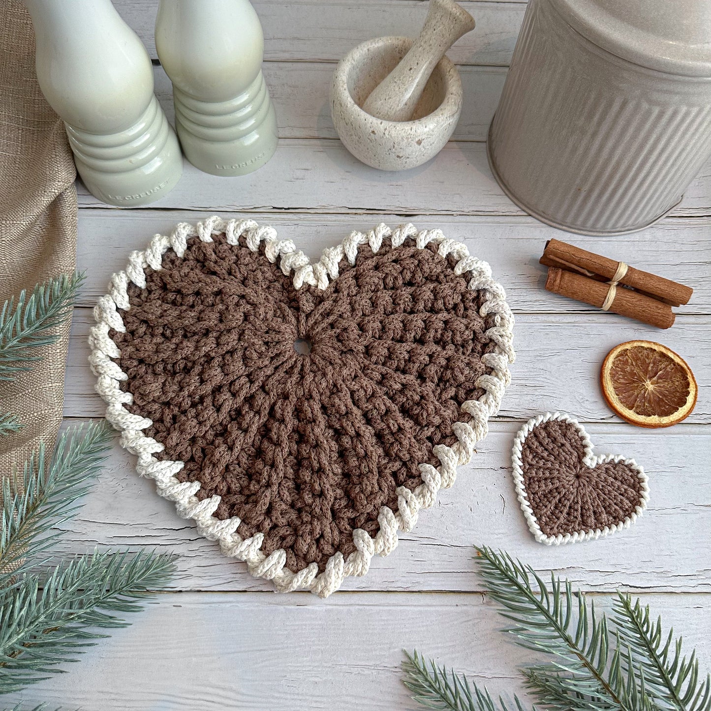 Crocheted heart-shaped trivet and coaster on a wooden surface with decorative items.