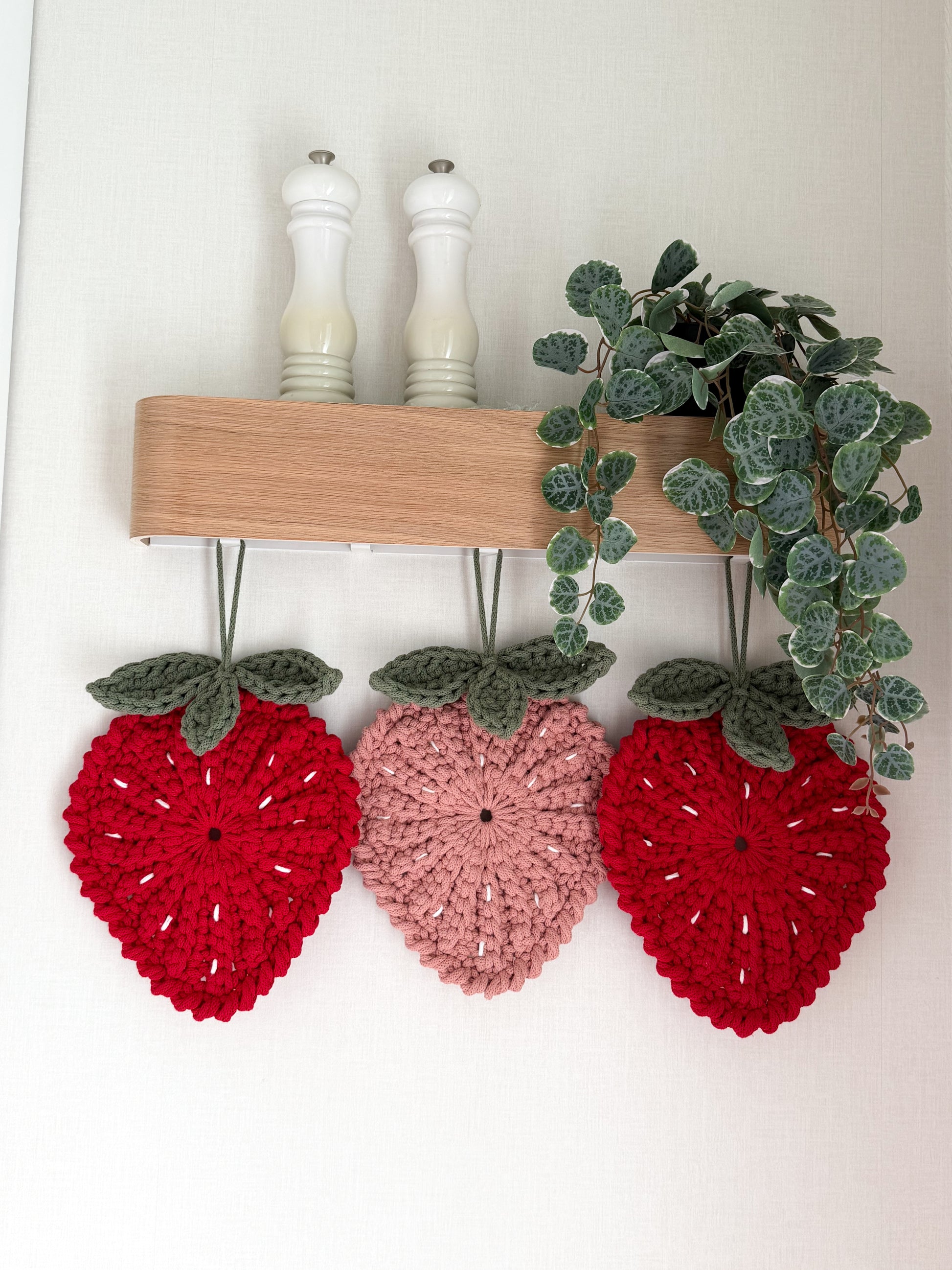 Three crochet strawberry trivets/wall hangings in two color variations
