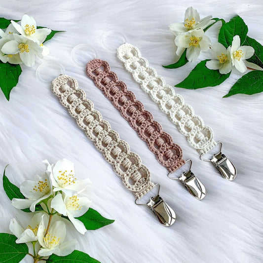 Crochet pacifier clip pattern Astrid with Scandinavian-inspired handmade baby styling and soft neutral textures.
