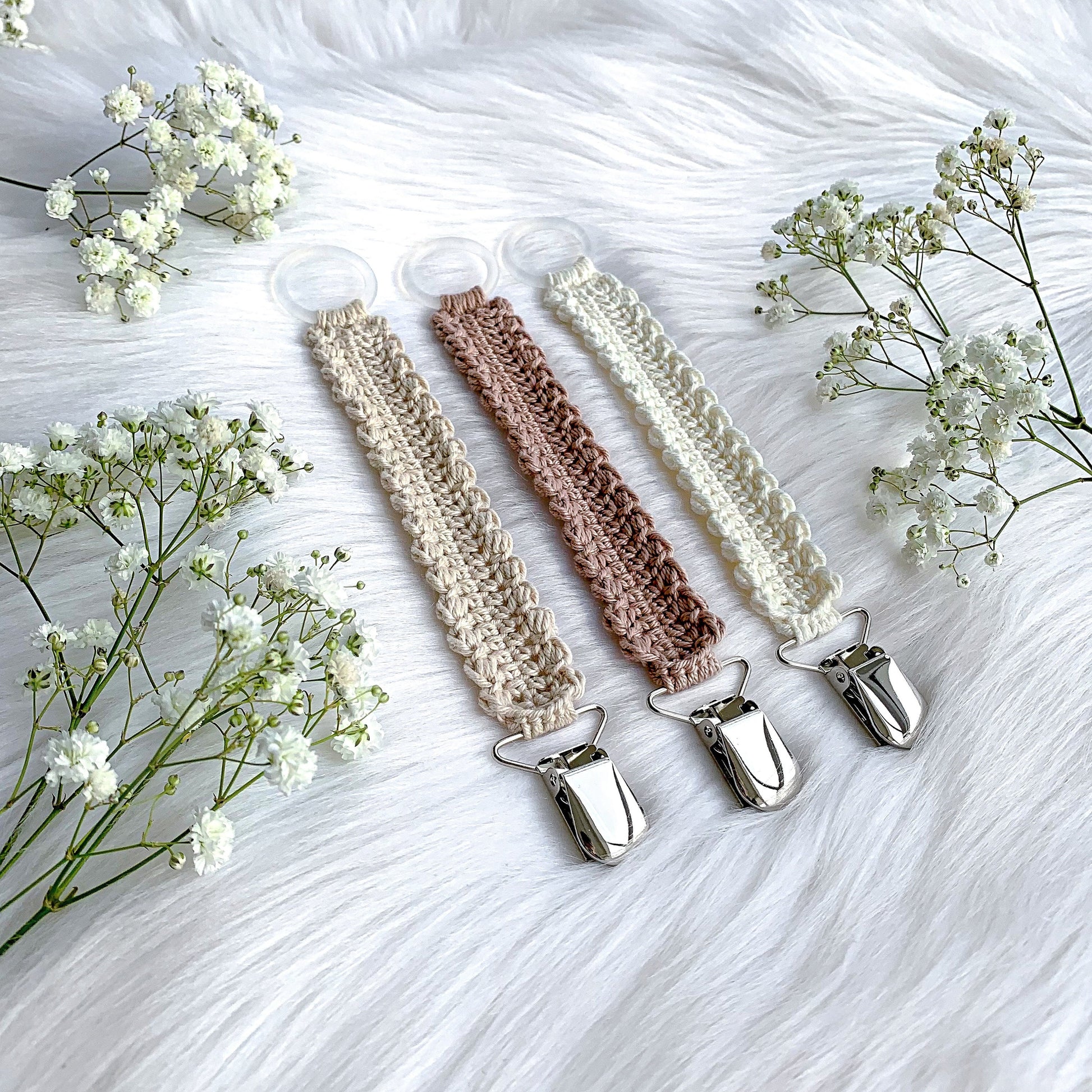 Handmade crochet baby accessory pattern featuring a soft textured pacifier clip for modern nurseries.