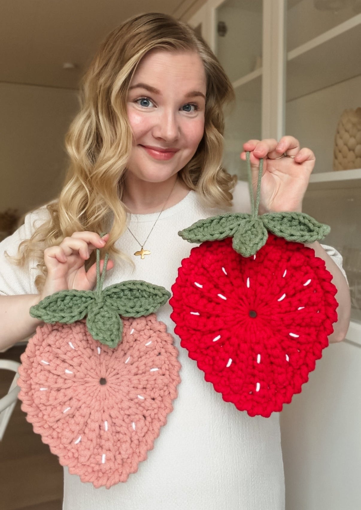 Crochet strawberry trivet pattern for modern kitchen decor. Animo Design founder holding it.
