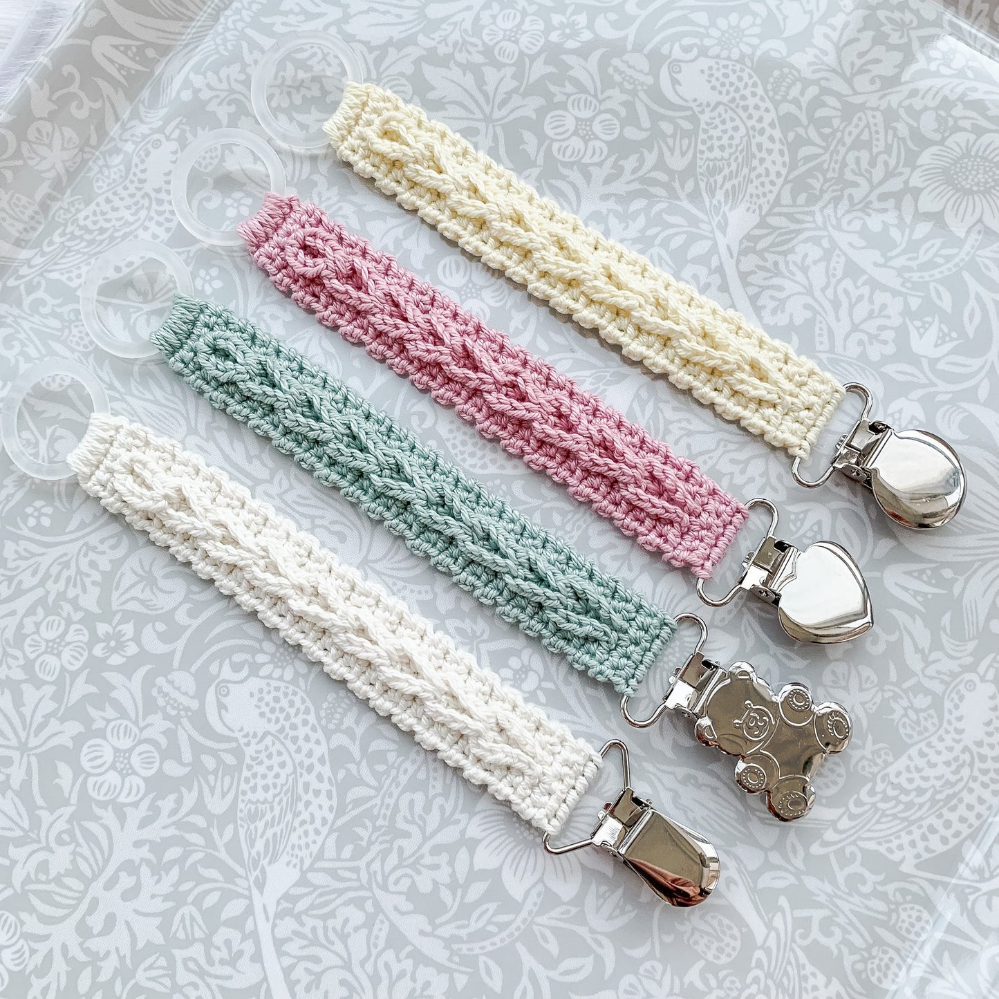 Modern crochet baby accessory pattern with cozy neutral styling and handmade pacifier clip design.