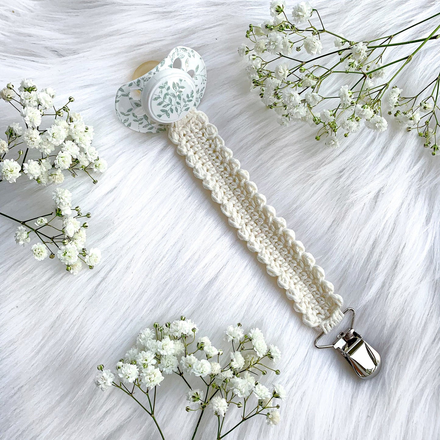 Neutral crochet pacifier holder pattern with cozy textures and Scandinavian nursery aesthetic.