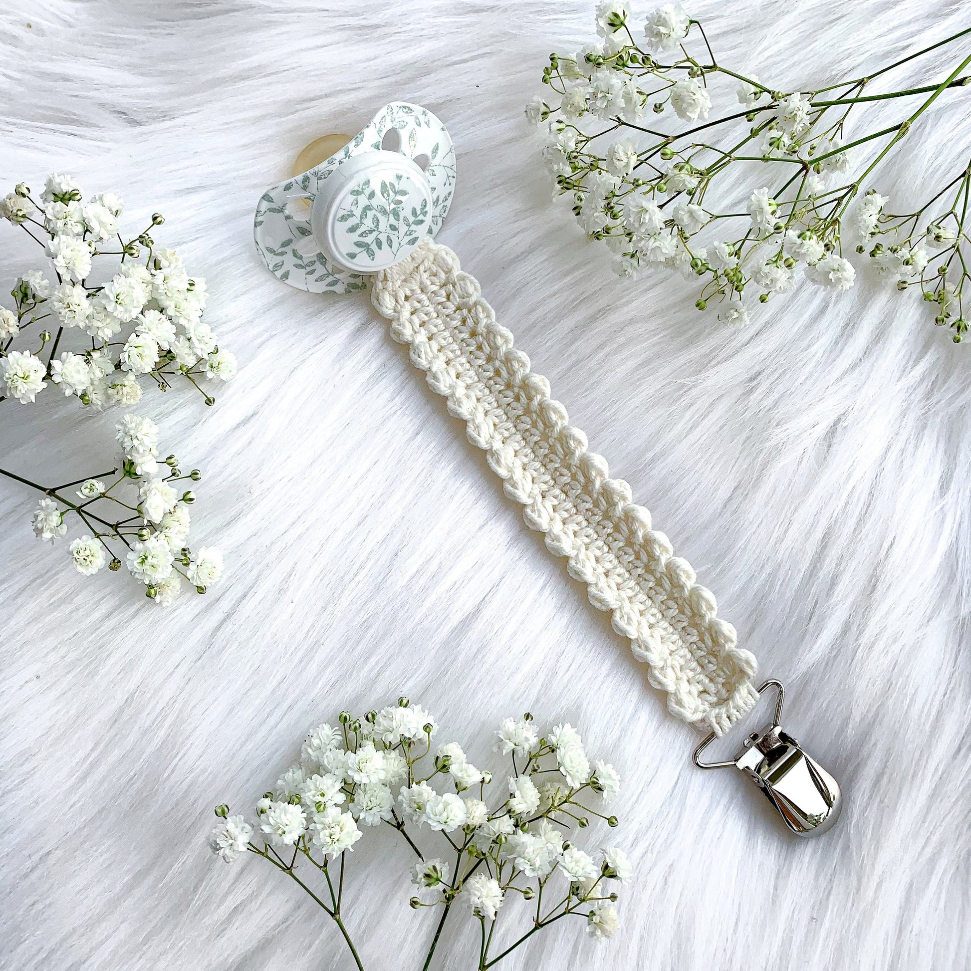 Neutral crochet pacifier holder pattern with cozy textures and Scandinavian nursery aesthetic.